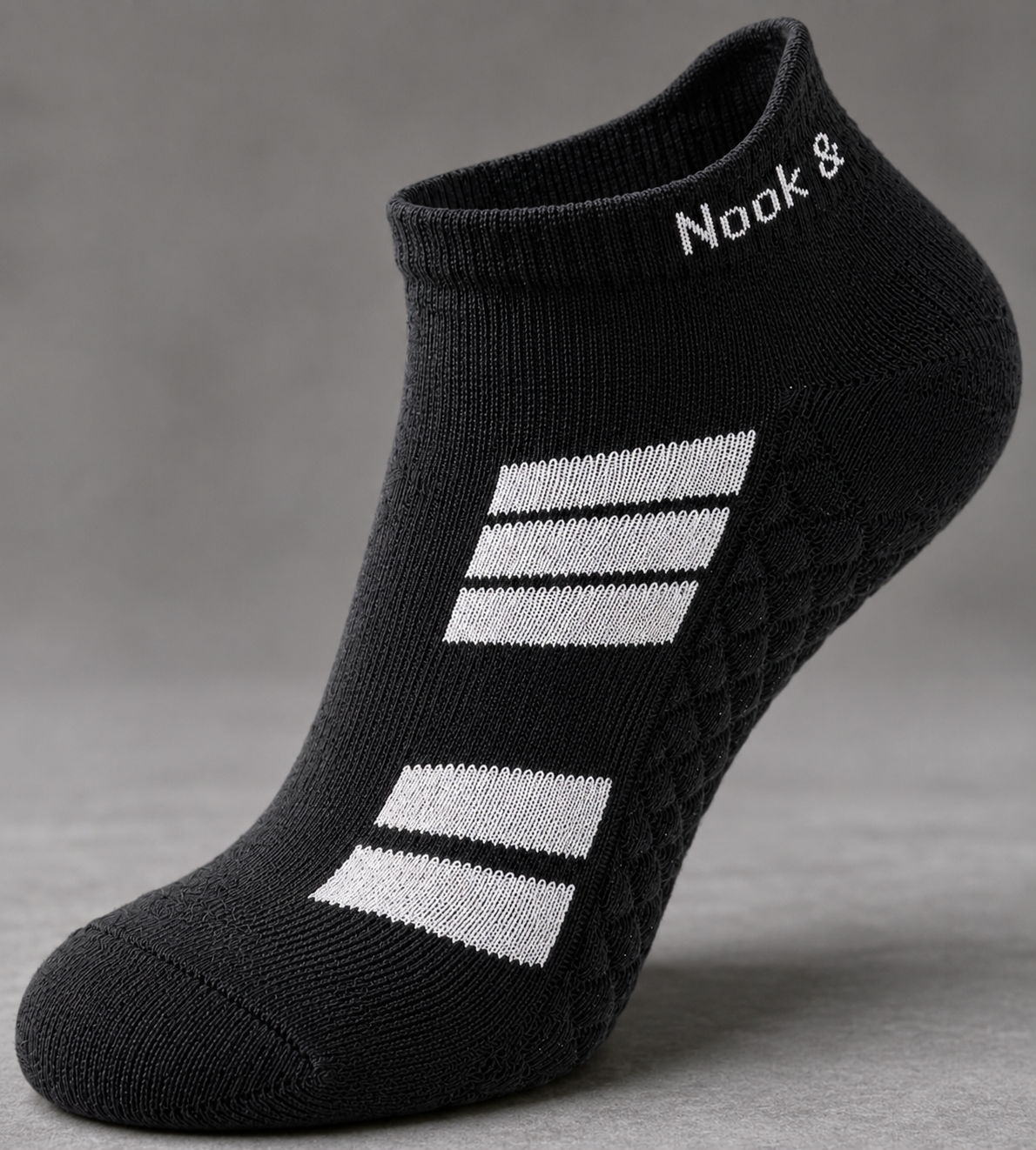 Black Nook and Stitch orthopedic ankle sock on a neutral gray studio background